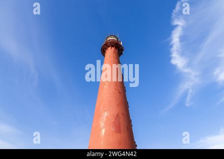 Looking up at the Andenes Lighthouse, its red silhouette contrasts with the soft cloud patterns in the blue Norwegian sky. Lofoten Islands Stock Photo