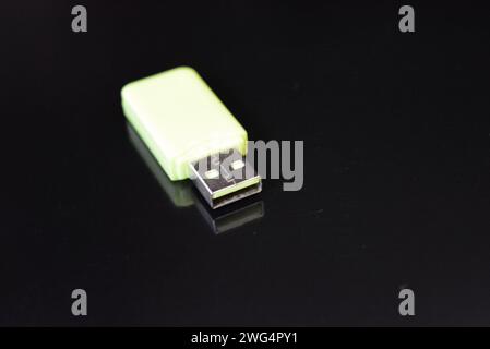 Bright light green computer USB flash drive for the accumulation and storage of information located on a black glossy surface. Stock Photo