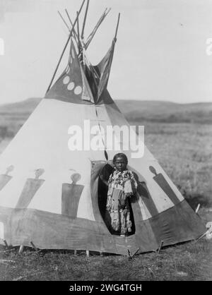 Crow Chief's Daughter, c1910. Piegan girl standing in doorway of tepee, wearing beaded buckskin dress, Montana. Stock Photo