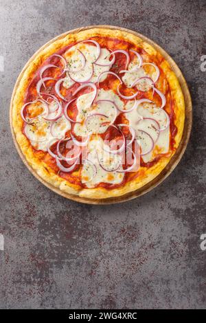 Pizza pugliese is a style of pizza in Italian cuisine prepared with tomato, onion, and mozzarella closeup on the wooden board on the table. Vertical t Stock Photo
