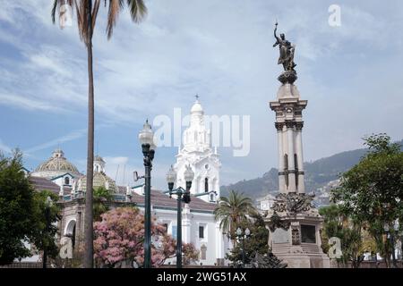 Old monument  and white church in main square of Quito Stock Photo