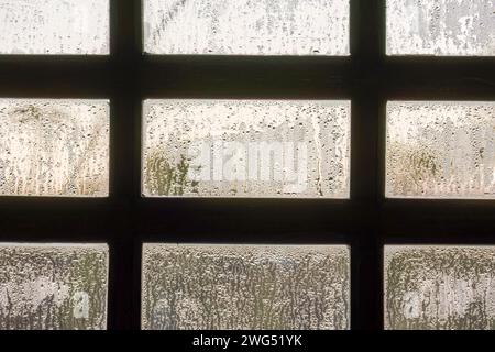 A paneled wooden window covered with the drops of early dew, in a farm house at the eastern Andes mountains of central Colombia. Stock Photo