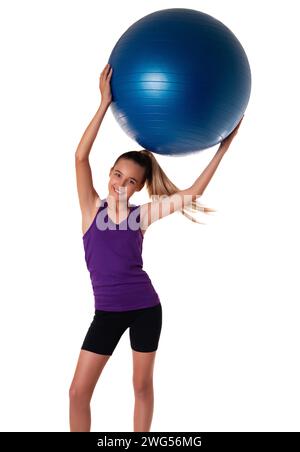 Slim and fit teen girl holding a swiss ball. Full length shot on white ...