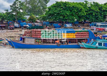 old ships loaded with colored oil barrels and a shore littered with plastic waste Stock Photo