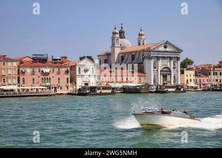 venice view from the water to the church of santa maria del rosario in front of a blue sky and a passing boat Stock Photo