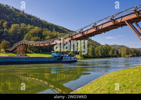 a barge is passing under the second longest wooden bridge in europe called tatzlwurm on the main-danube canal in sunny weather and beautiful reflectio Stock Photo