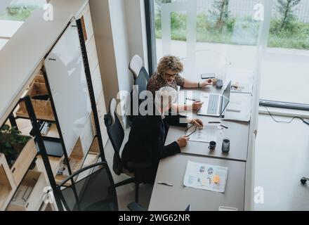Multigenerational group of diverse coworkers collaborating on a successful project in a modern co working space. Stock Photo