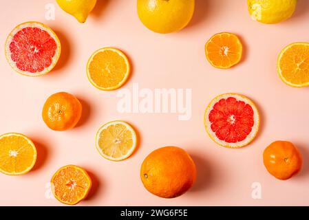 Collage of citrus fruits, whole, half and sliced, grapefruits, oranges, lemons and tangerines on a pink background. Stock Photo