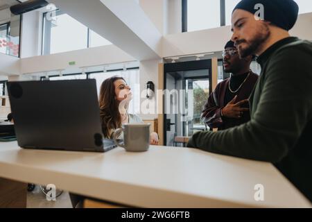 Three colleagues collaboratively solving business issues in a well-lit, contemporary office space, portraying teamwork and engagement. Stock Photo