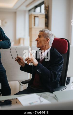 Senior business executive engaging in discussion at office meeting Stock Photo