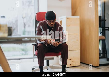 Stylish man in casual business attire engrossed in his smart phone in a modern office Stock Photo