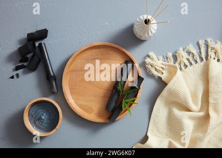 Activated charcoal mask in a bowl, black bamboo and a towel with a bird's-eye view. Blank space on the tray to insert the product Stock Photo