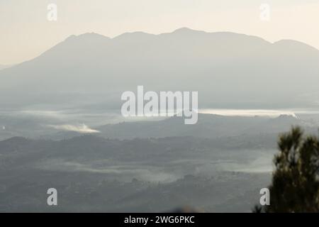 Backlit landscape during foggy morning in the Cocentaina valley and silhouette of the La Serrella mountain range from Alcoy, Spain Stock Photo