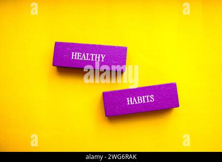 Healthy habits lettering on purple wooden block with yellow background. Conceptual symbol. Copy space. Stock Photo