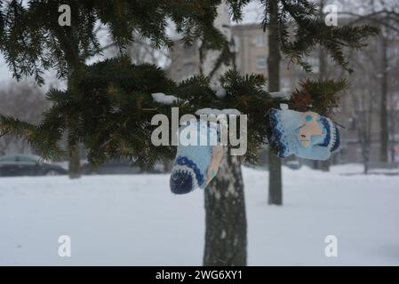 On the embankment of the river Dnipro stands a Christmas tree with children's gloves on it in the snow, in winter in cold weather. Stock Photo