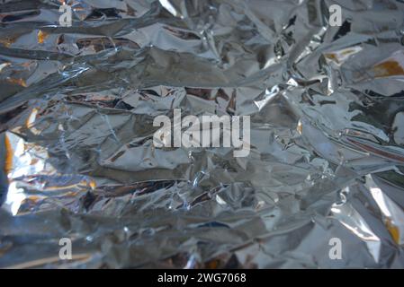 Stylish metallic, gray, reflective melik background. Festive background with brightness and light effects and gloss on silver crumpled film. Stock Photo