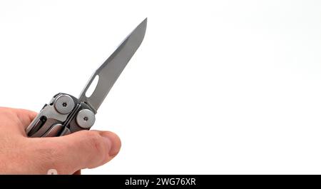 On a white background, a man's hand holds a steel multi-tool with an open knife blade. Pocket folding knife. Portable multi-tasking multi-tool with ma Stock Photo