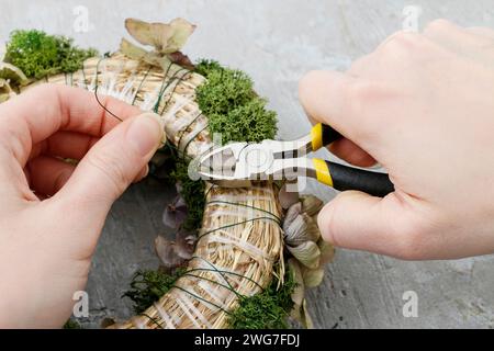 Florist at work: how to make christmas door wreath with moss and dry hortensia flowers. Step by step, tutorial. Stock Photo