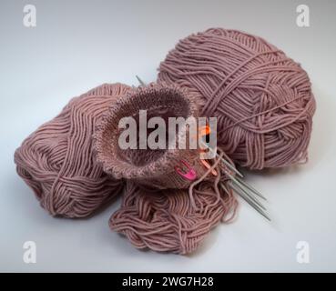 knitting from pink wool and knitting needles on a white background Stock Photo