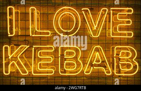 Neon shining sign in yellow warm color on a brick wall with the inscription or slogan I love kebab. Brick wall, background. Bright electric neon light Stock Photo