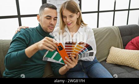 A couple examines paint swatches together on a couch in a well-lit living room, planning a home renovation. Stock Photo