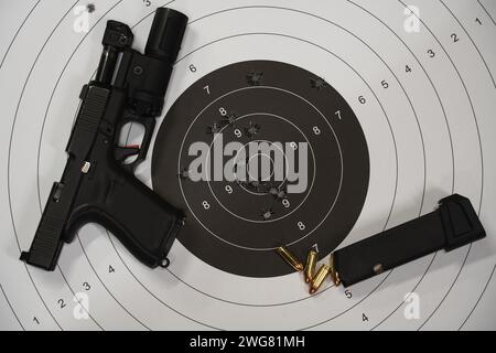 Tactical pistol with a flashlight and a shooting target with bullet holes in the center. High quality photo Stock Photo