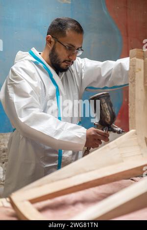 lifestyle of young man using lacquer gun for painting, craft work tools on furniture, workplace Stock Photo