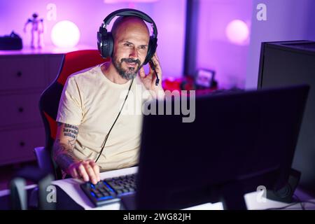 Young bald man streamer playing video game using computer at gaming ...