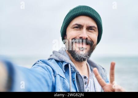 Young bald man smiling confident making selfie by camera at seaside Stock Photo