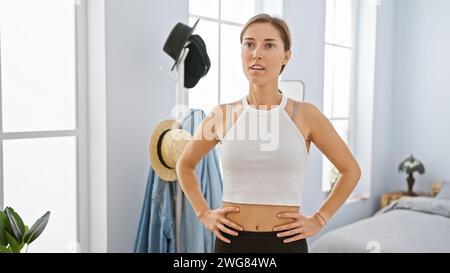 A young caucasian woman stands confidently in a bedroom, exuding youth and casual elegance. Stock Photo