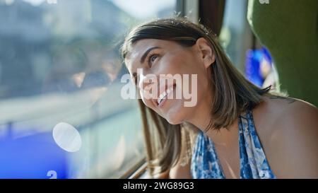Cheerful, beautiful hispanic woman enjoying her railway journey, smiling while looking through the train window Stock Photo