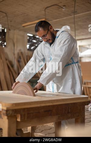person working in carpentry, young man at workplace with industrial machinery, assembling wooden furniture, machines and lifestyle, professional occup Stock Photo