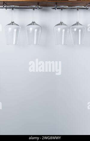 Wine glasses dangle from a wooden rack. blank space for text or graphics. Stock Photo