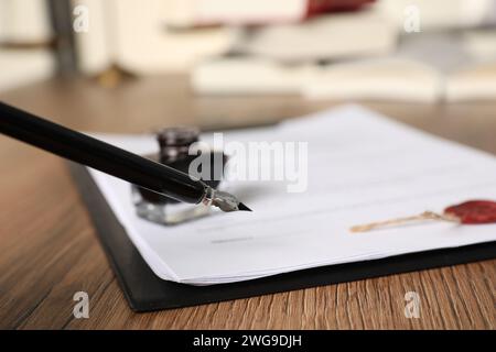 Signing document with fountain pen on wooden table, closeup. Notary contract Stock Photo