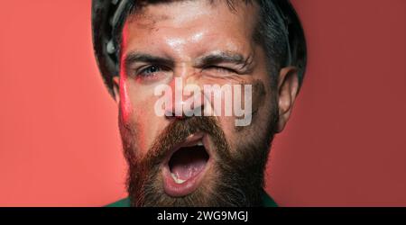 Closeup portrait of funny bearded man in protective helmet. Construction worker in hard hat. Male builder, architect or engineer in safety hardhat Stock Photo