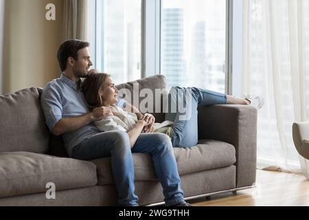 Peaceful couple in love daydreaming relaxing on sofa at home Stock Photo