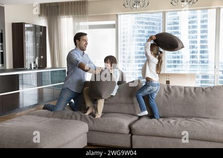 Father and kids fighting with pillows on couch Stock Photo