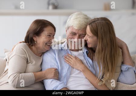 Cheerful adult woman hugging older senior parents Stock Photo