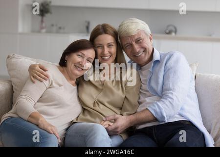 Happy adult daughter enjoying meeting with senior parents at home Stock Photo