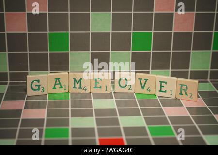Wooden tile with green game over text on a blocked background Stock Photo
