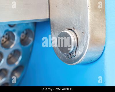 Stamped external retaining ring on a stud bolt of an industrial twin screw press. Shallow depth of field with the retaining ring in focus. Stock Photo