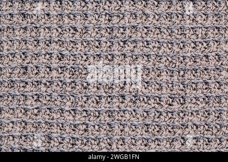 A fragment of a knitted warm sweater made of wool threads in a beige shade. Stock Photo