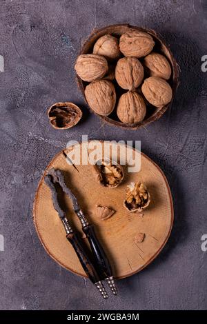 shelled walnuts and an old nutcracker on a wooden disc. A bowl with the whole walnuts aside. view from above Stock Photo