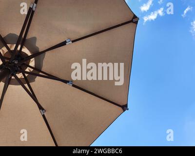 Low angle view of an opened beach fabric umbrella against the blue sunny sky, view from under parasol, holiday or vacation concept, with copy space Stock Photo