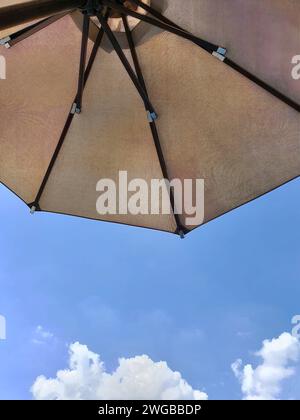 Low angle view of an opened beach fabric umbrella against the blue sunny sky, view from under parasol, holiday or vacation concept, with copy space Stock Photo