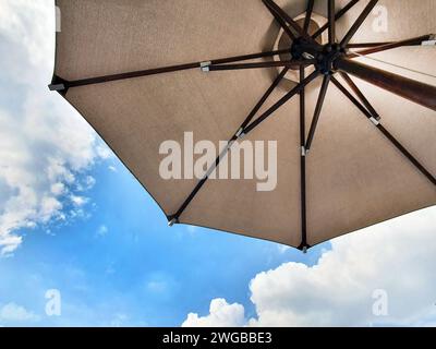 Low angle view of an opened beach fabric umbrella against the blue sunny sky, view from under parasol, holiday or vacation concept, with copy space Stock Photo