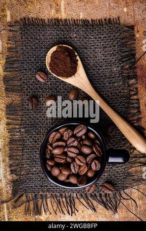in the foreground, from above, the roasted coffee beans in the cup and the ground coffee in the spoon. Stock Photo
