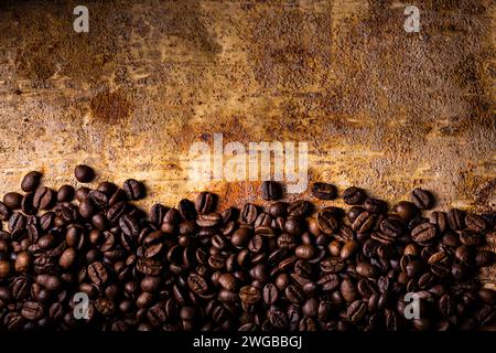 In the foreground, from above, on the textured brown rustic background, roasted coffee beans. Blank space for your text Stock Photo