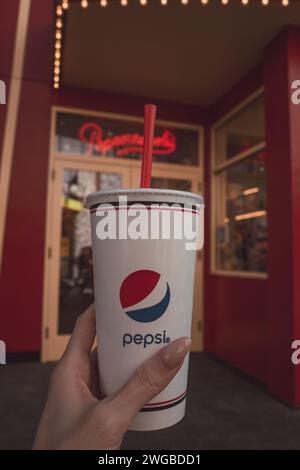 Female hand holding a plastic cup with Pepsi Cola and a red straw Stock Photo