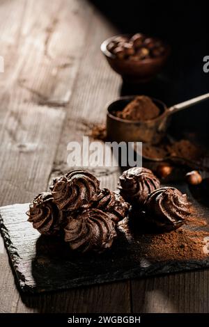 in the foreground, in a dark environment, chocolate kisses with hazelnuts and cocoa powder. Stock Photo